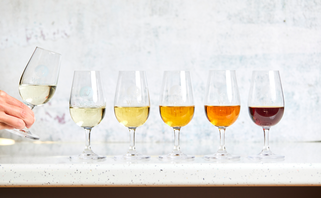 Different coloured sake in small wine glasses, arranged from light yellow to deep red