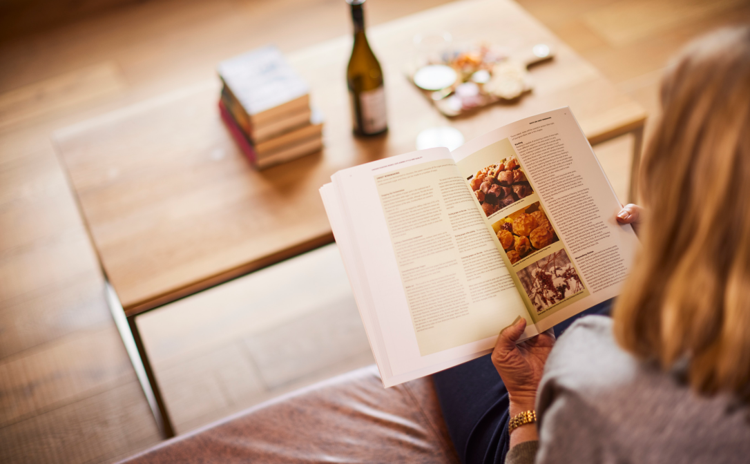 A person sitting on a sofa while paging through the Level 3 Award in Wines textbook.